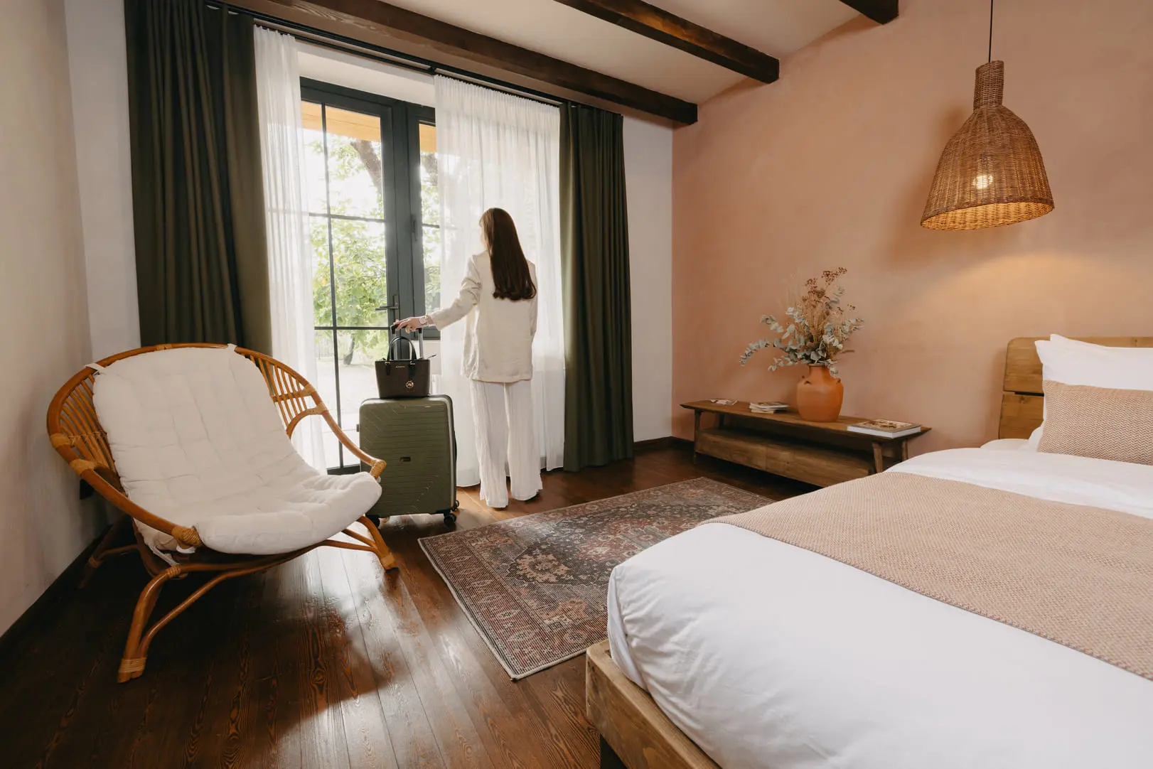 A guest arriving with her suitcase in a room with a balcony