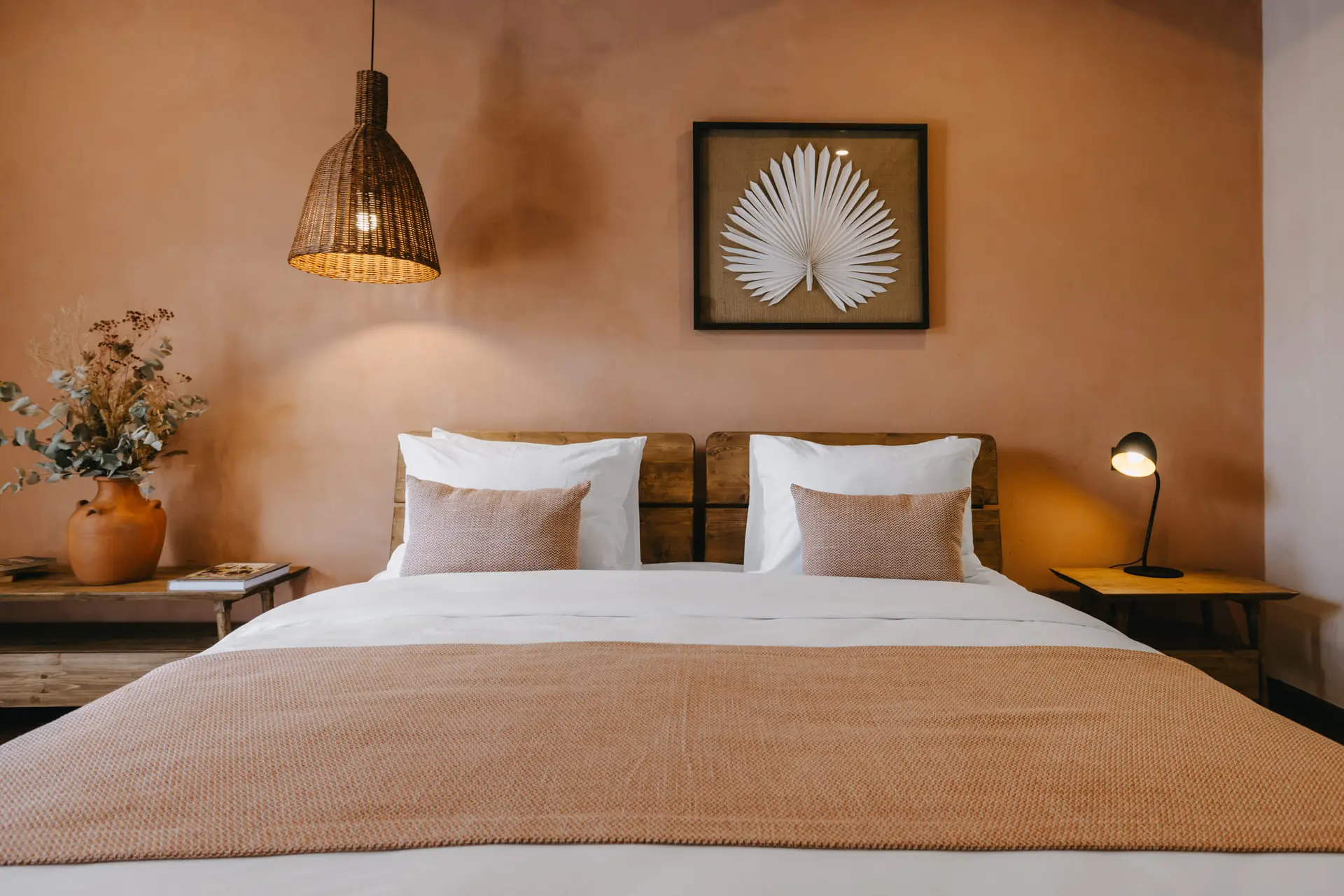Double room with a wide bed, a wicker lamp and a palm leaf on the wall