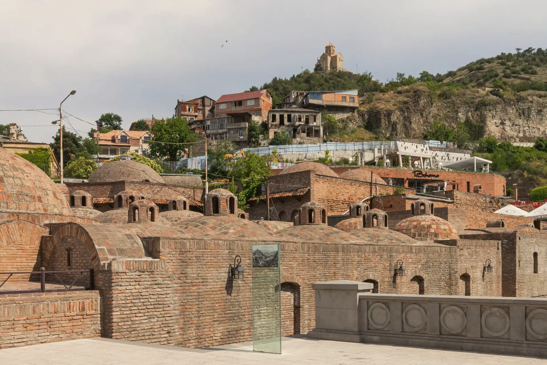 Brick domes of the sulphur baths in Abanotubani, with old houses and a hilltop church above