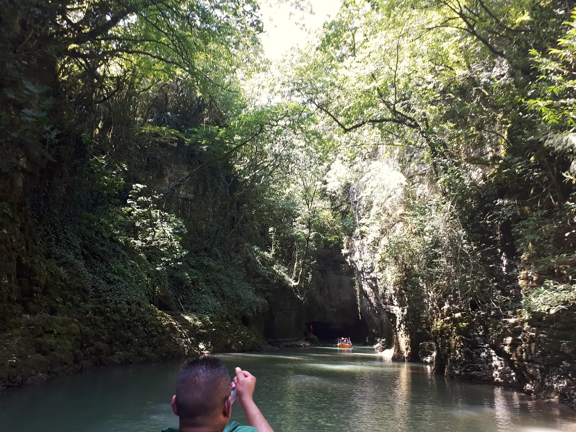 A boat on the river between the green walls of Martvili Canyon