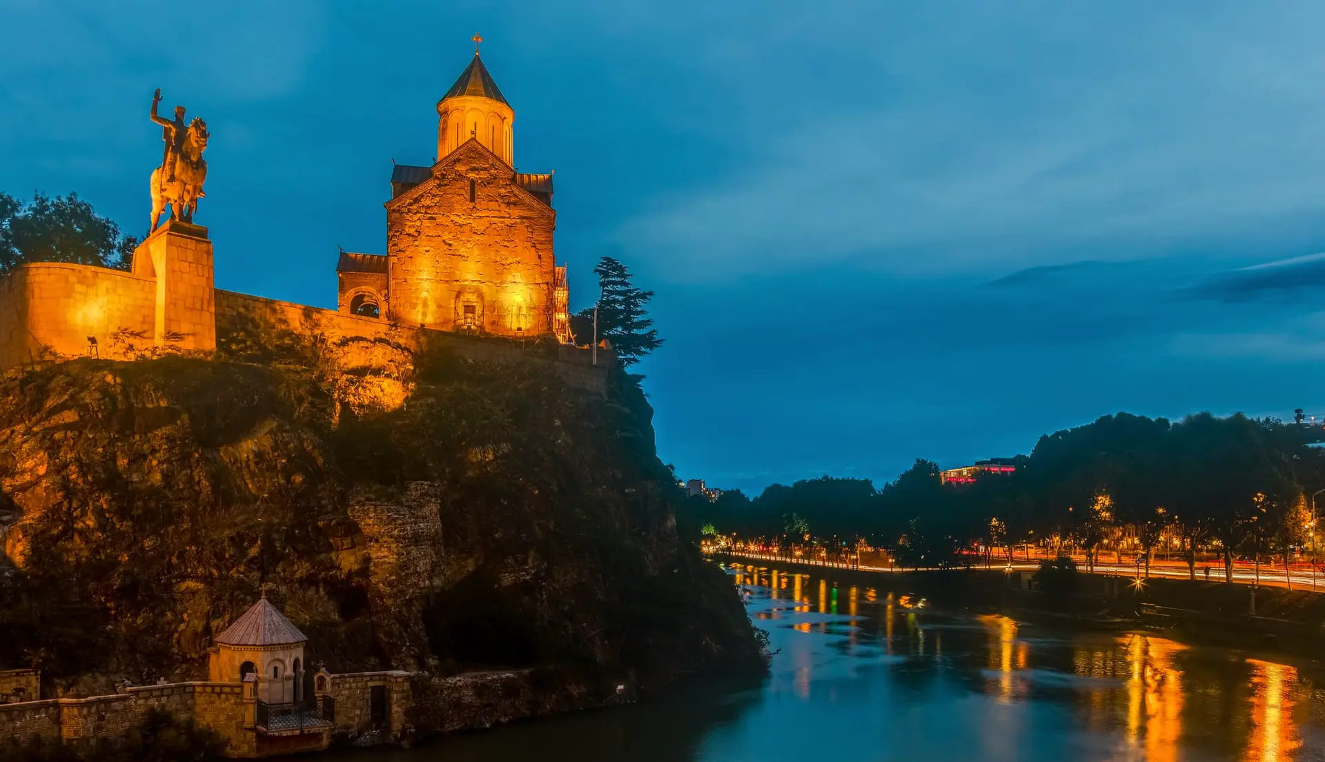 Metekhi Church and the statue of King Vakhtang Gorgasali lit up at dusk above the Mtkvari river in Tbilisi