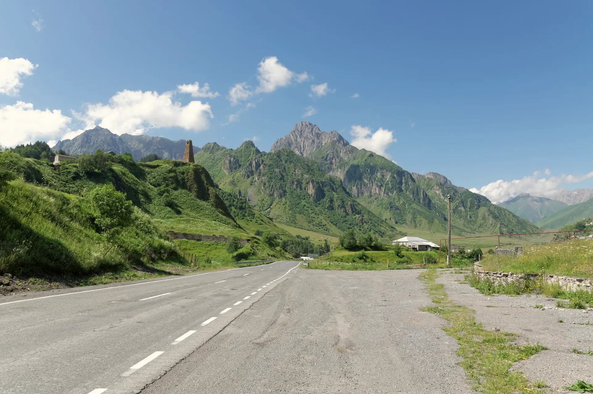 A paved mountain road through a green valley of the Caucasus in summer
