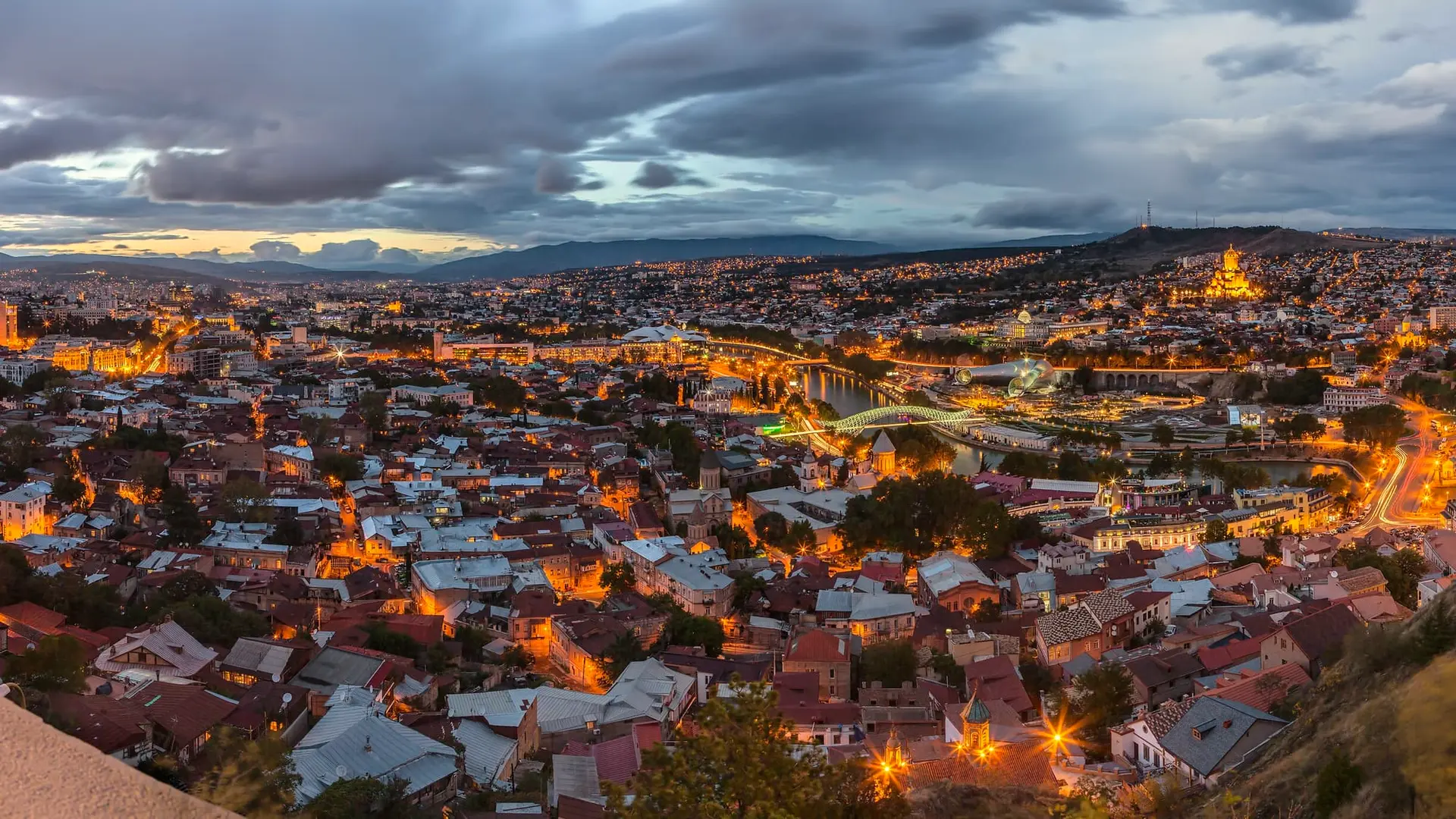 Tbilisi at dusk from Narikala, with the old town, the Peace Bridge and car lights along the river